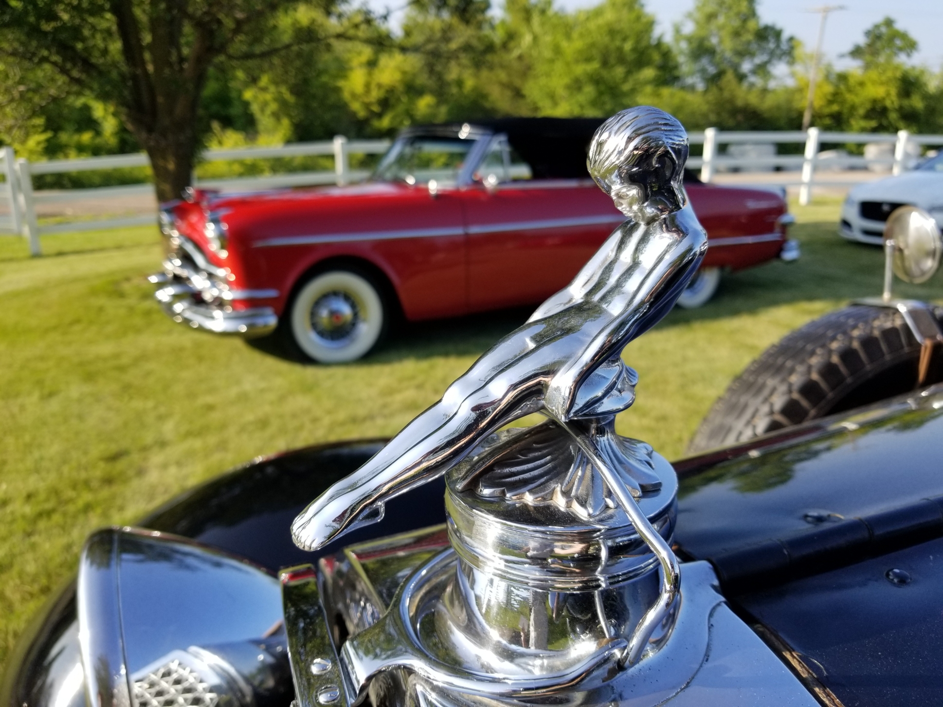 Hood Ornament of 1929 Packard 633 Runabout in front of 1954 Packard Convertible in Red