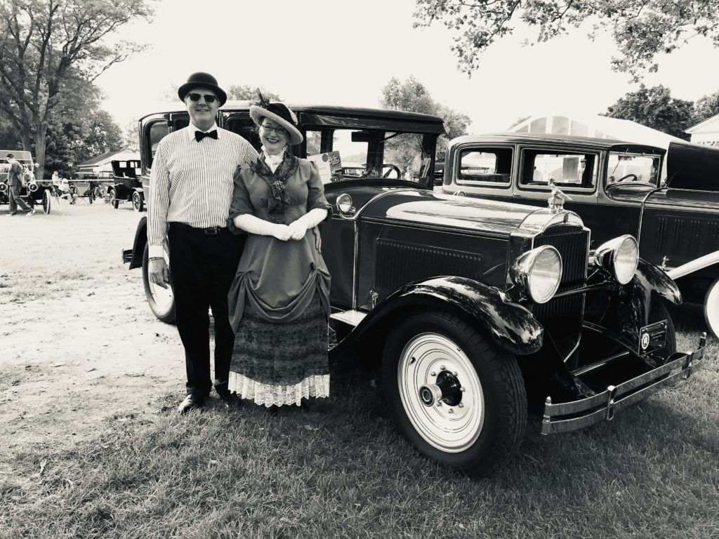 a black and white image of a 1929 Packard with two people dressed in costume at the Old Car Festival at Greenfield Village