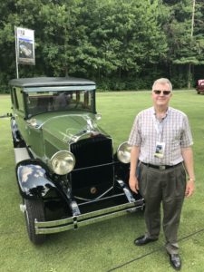 1929 Packard with a man standing next to it at the Concours d'Elegance of America