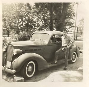 Circa 1963 image of a man posing next to a 1937 Packard Eight Coupe