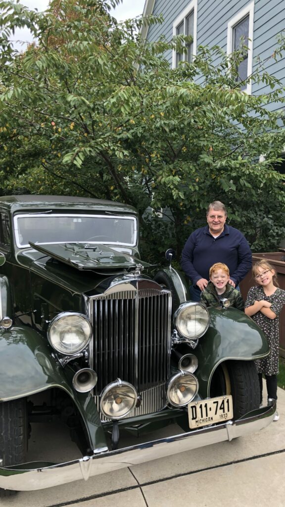 Green Packard with a man and two children next to it