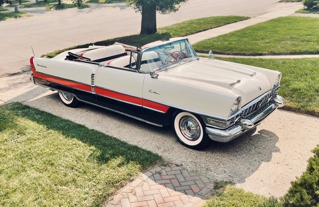 White Packard Carribean convertible with red and black bottom parked on a driveway in a neighborhood